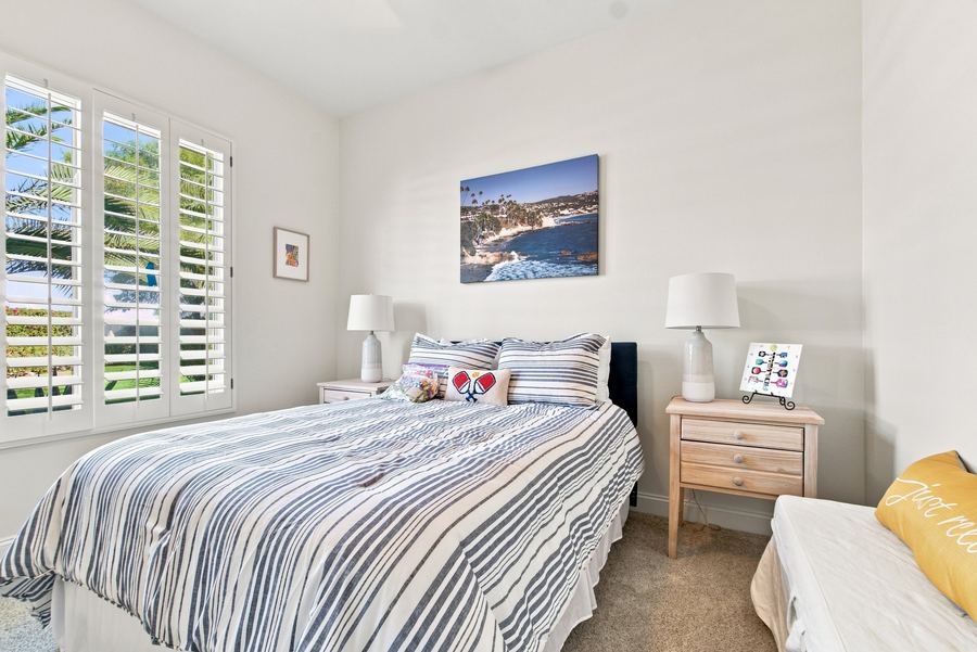 Bedroom with striped bedding and plantation shutters