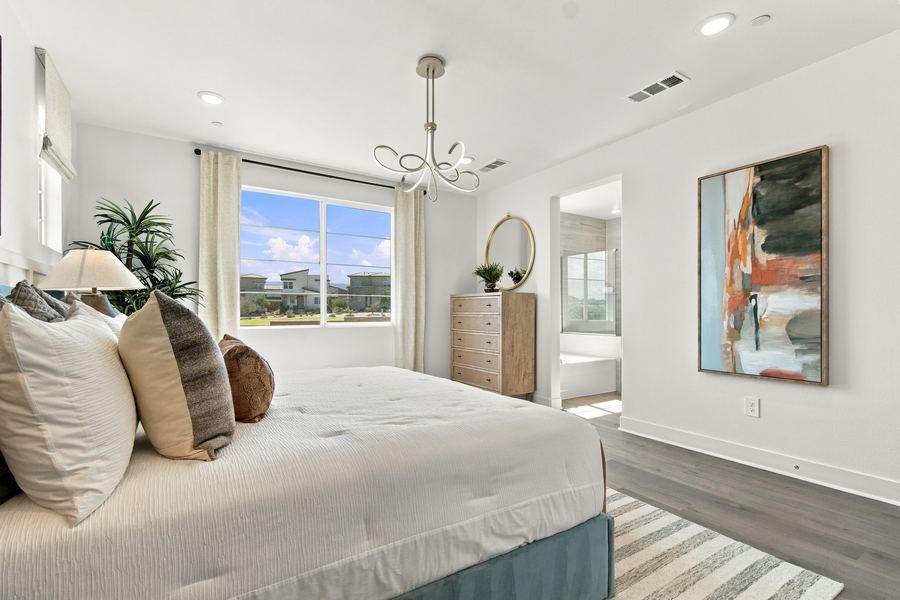 Primary bedroom with upholstered bed and abstract artwork