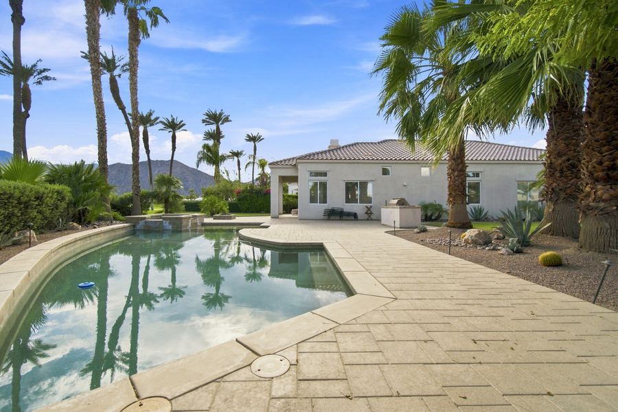 Backyard pool and paver patio with palm trees and mountain backdrop